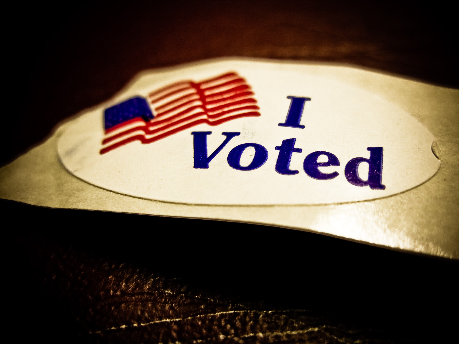 A sticker with the words "I Voted" and the American flag image next to it lays on a table. Photo courtesy of Flickr-Photo Sharing.