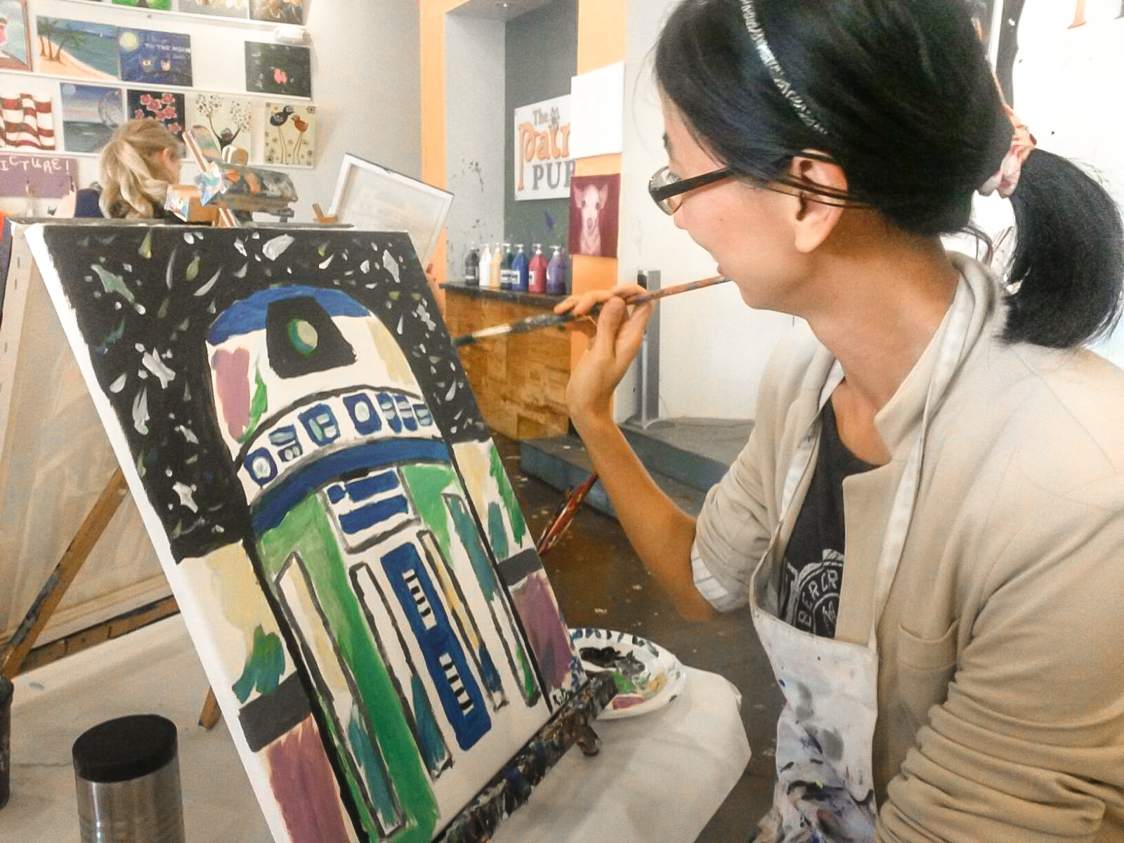 Photo: Xiaodong Ma painting R2D2 at The Paint Pub. Photo Courtesy of Rios Desdamona.