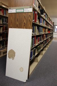 Large ceiling tile is propped up against bookshelf in the library. Photo by The Signal Reporter Amethyst Gonzalez.