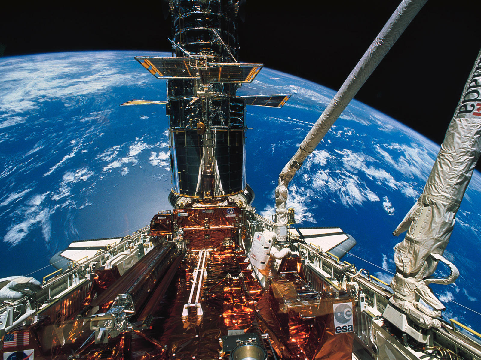 PHOTO: Astronaut F. Story Musgrave moves about in the Space Shuttle Endeavour's cargo bay during the deployment of the solar array panels on the Hubble Space Telescope (HST) during the final of five STS-61 space walks. The left hand of astronaut Jeffrey A. Hoffman appears at lower left corner. Photo courtesy of NASA.