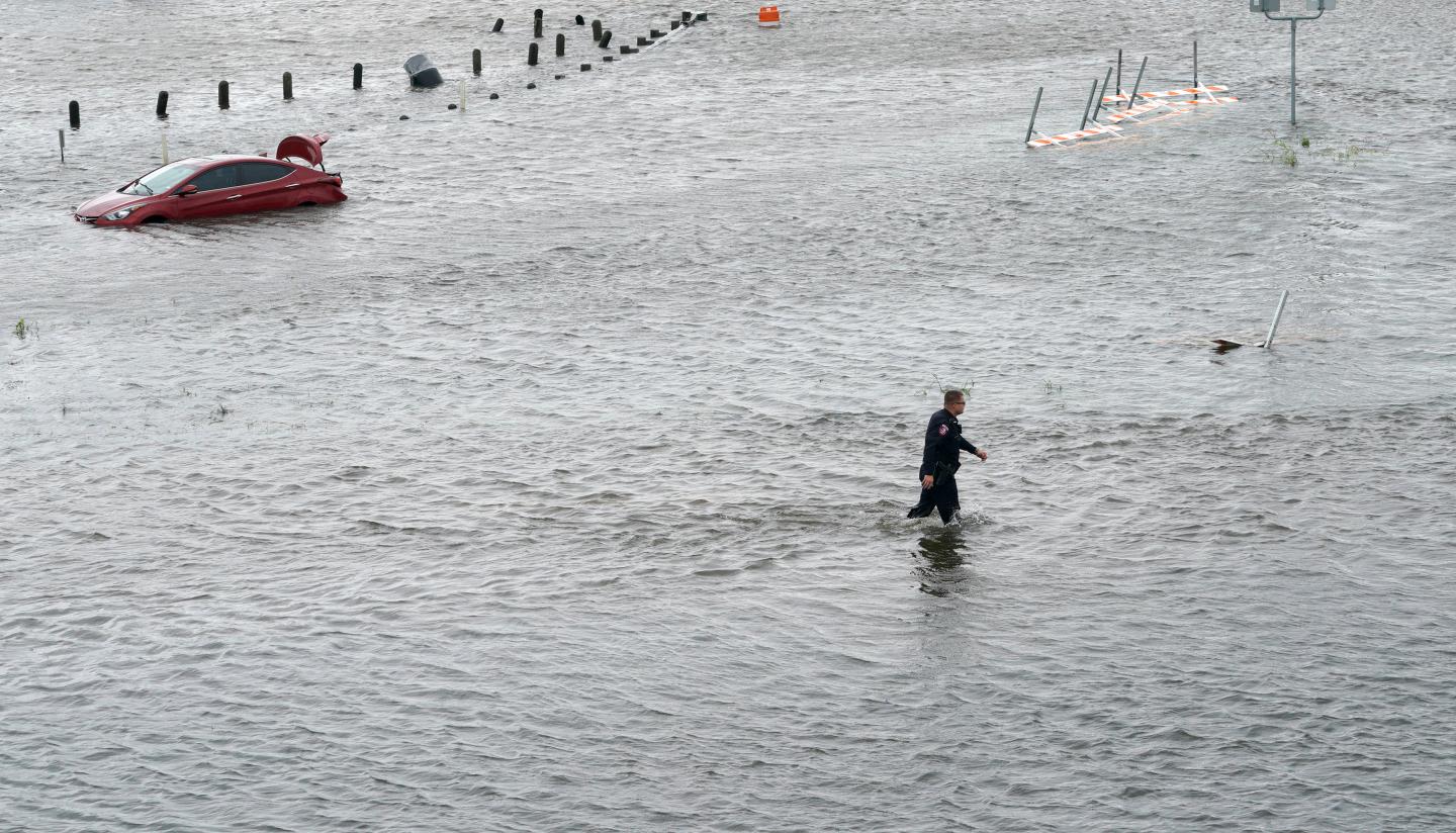 PHOTO: Police officer wades through water to check on a submerged vehicle in Alvin, Texas. Photo courtesy of Rick Wilking/Reuters.