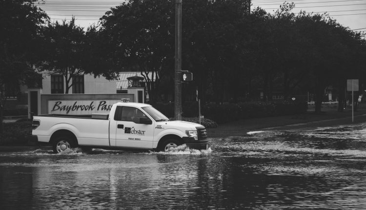 PHOTO: The City of Webster public works vehicle drives through flood waters at the intersection of Bay Area Boulevard and Gatebrook Drive. Photo by Audience Engagement Coordinator Regan Bjerkeli.