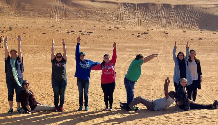 PHOTO: UHCL students and faculty show school spirit in Omani desert. Photo courtesy of Carolyn Toombs, graduate sociology major.