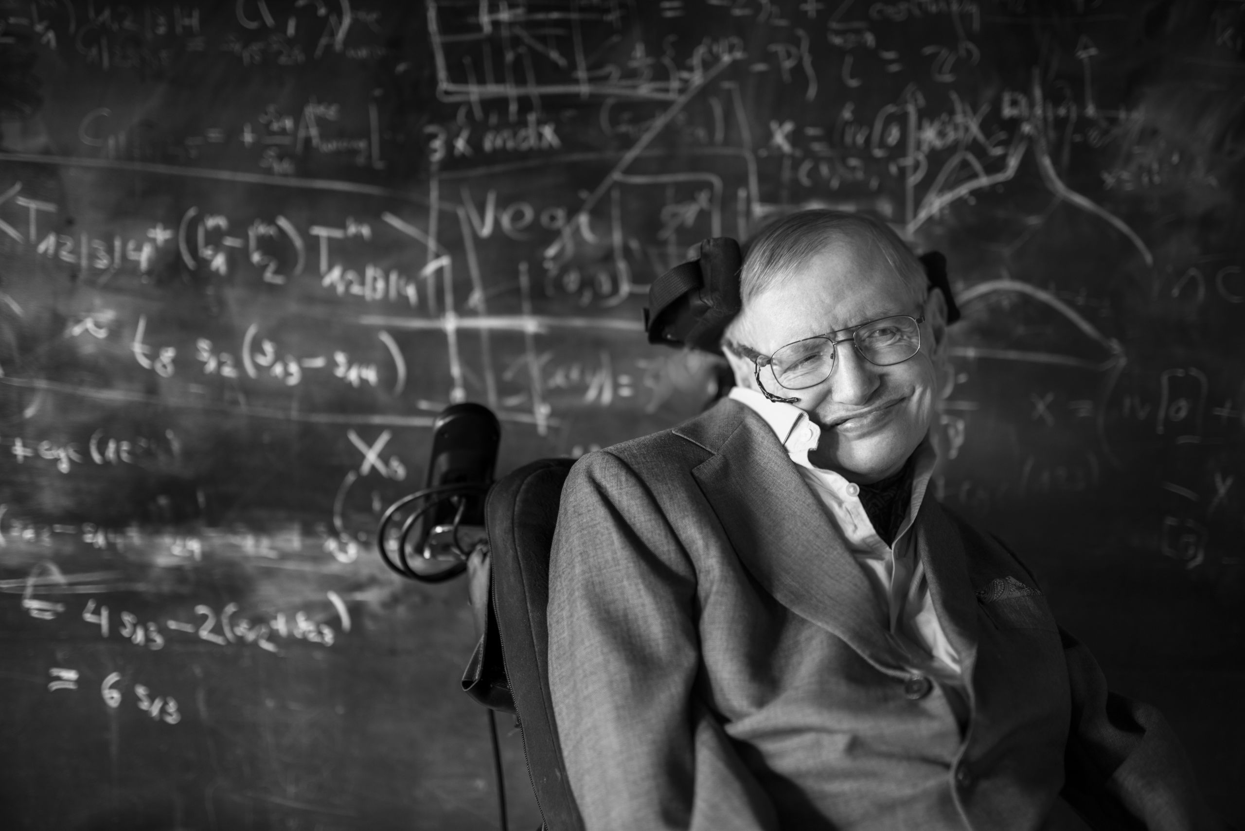 Stephen Hawking posing in front of chalk board. Photo courtesy of University of Cambridge.