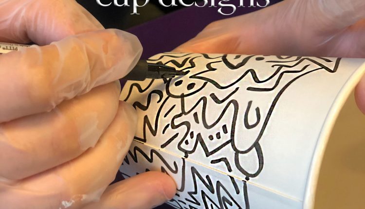 Jason Case used markers to design several cups for students to enjoy when visiting the Patio Cafe. Photo by The Signal reporter Kathryn King.