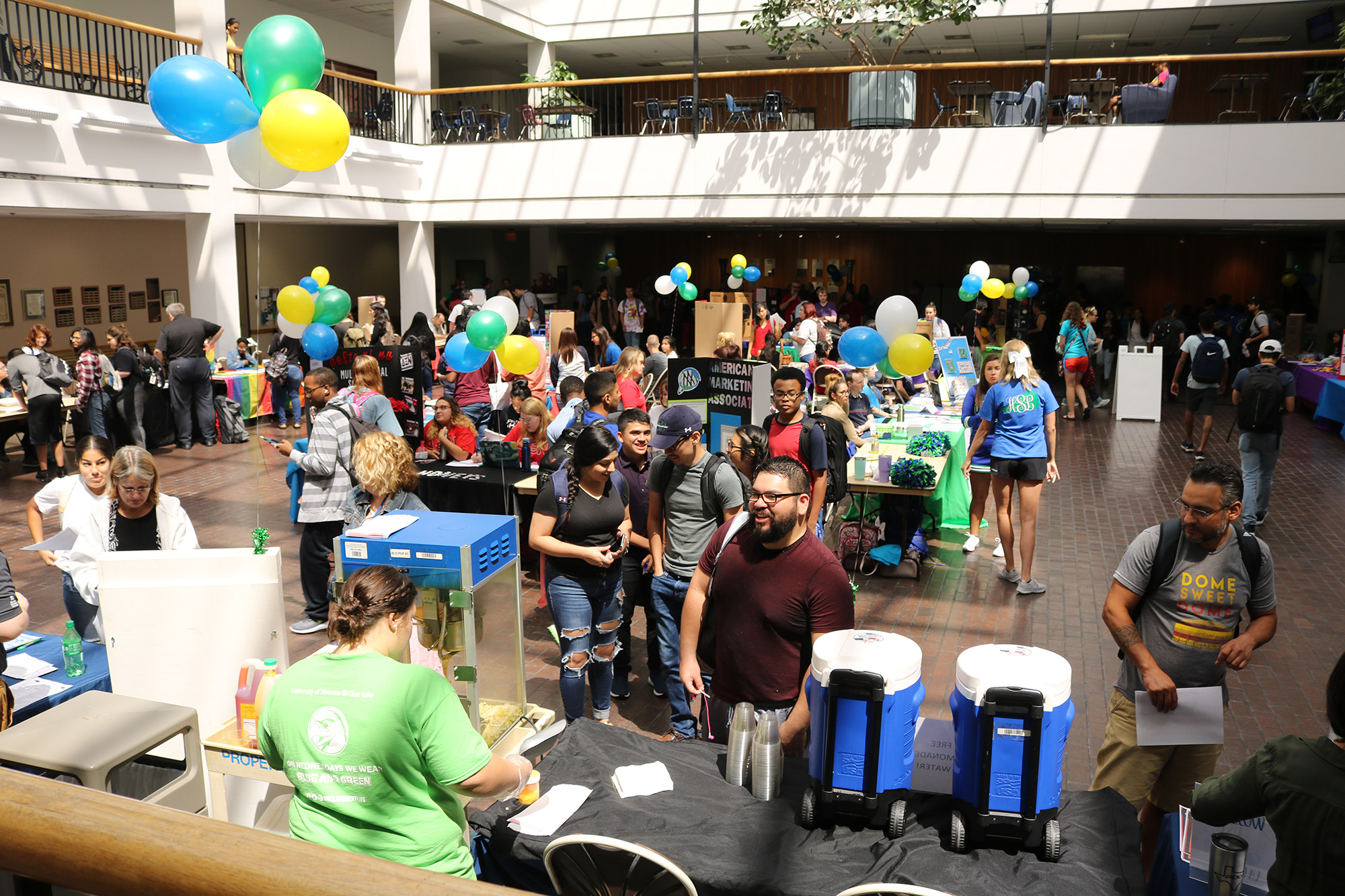 Students enjoy the Student Orgs Expo by getting popcorn. Blue, green, and yellow balloons are also in the scene.