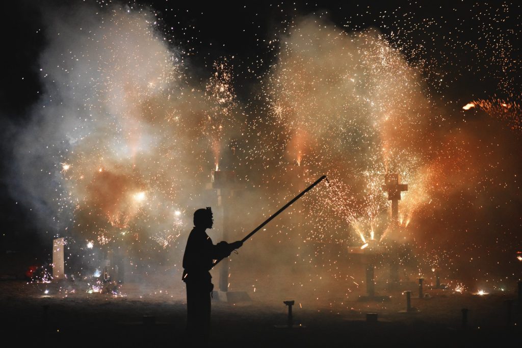 PHOTO: A team member of the Texas Renaissance Festival staff lights the ground based fireworks, silhouetted by the light. Photo courtesy of Matthew Smith