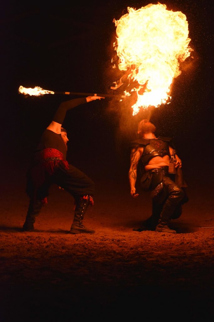 PHOTO: A fire performer holds a flame stick above another perform as he spits an accelerant into the flames to cause an explosion of flames. Photo courtesy of Matthew Smith