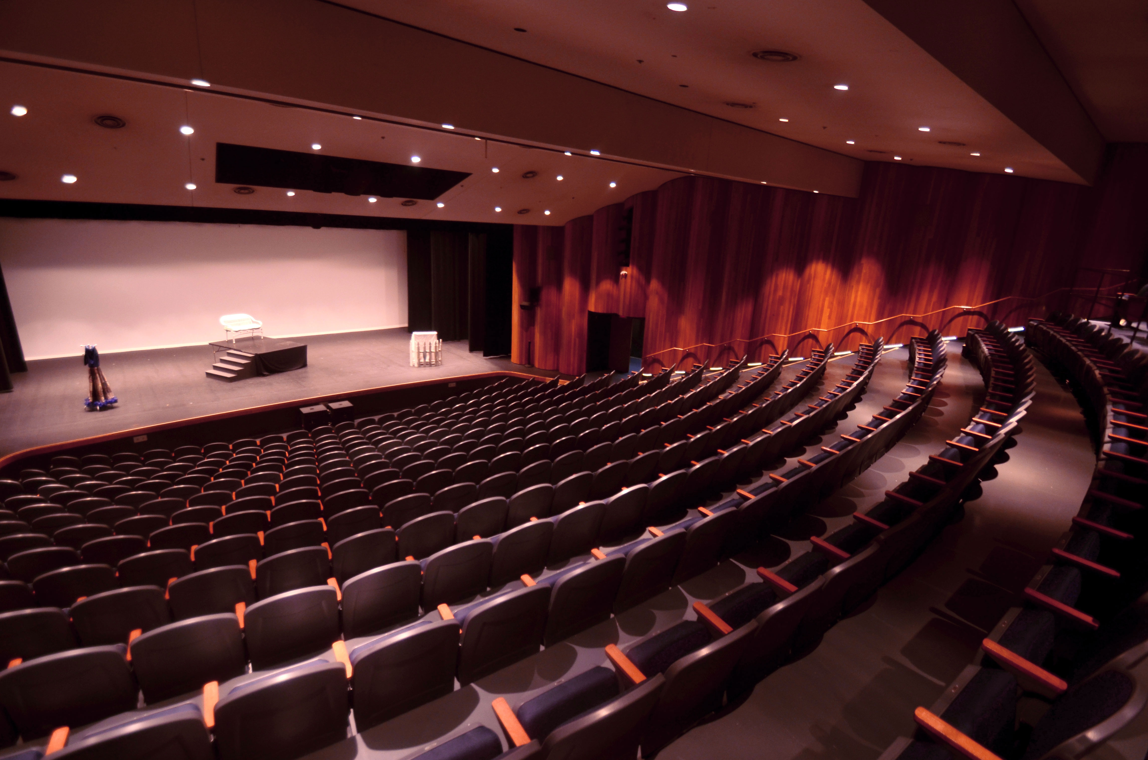 Image of an empty theater with a stage that has minimal set pieces.