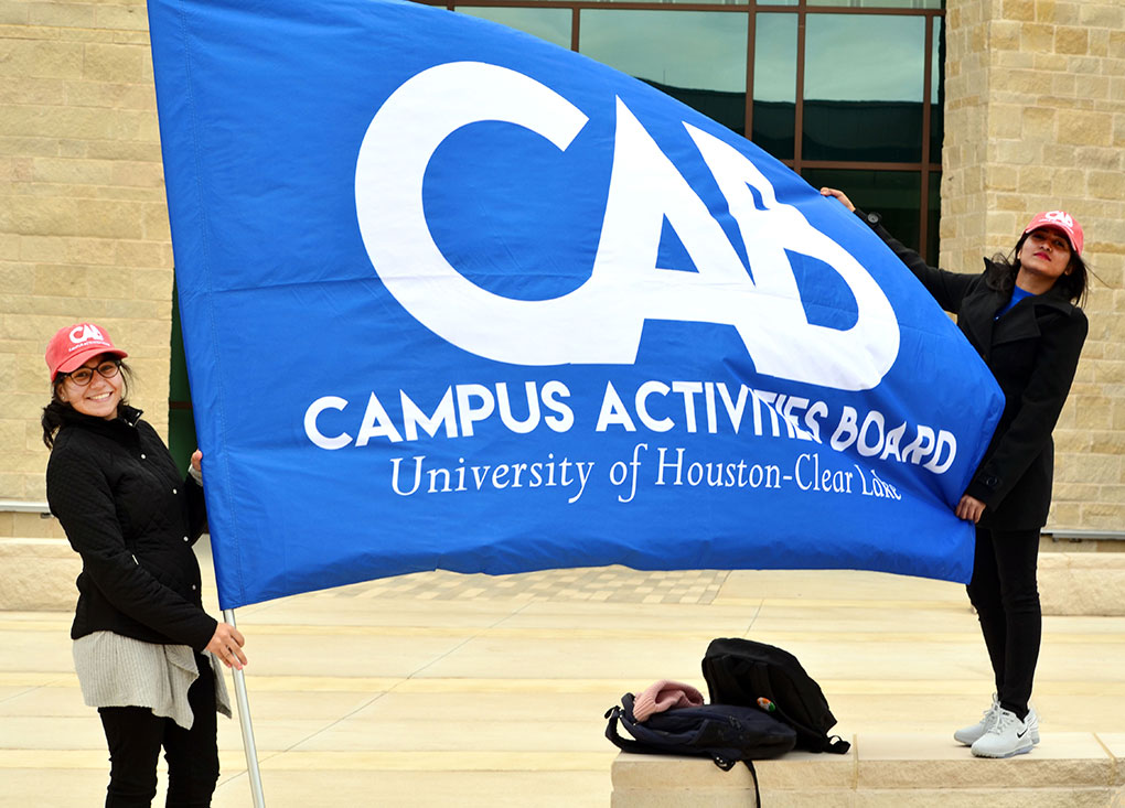 PHOTO: Sadhvi Eswara, left, and Vasundhara Kakda, members of the Campus Activities Board, hold the group’s flag as the Winter Wonderland festivities are being set up on Jan. 30, 2019 between the UHCL campus’s new STEM building and rec center. Photo by The Signal reporter Jennifer Martinez.