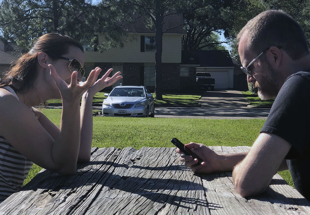 PHOTO: A man and a woman are sitting at a park bench, she is talking with her hands and he is looking at his mobile device. Photo by The Signal reporter Kathryn Wickenhofer.