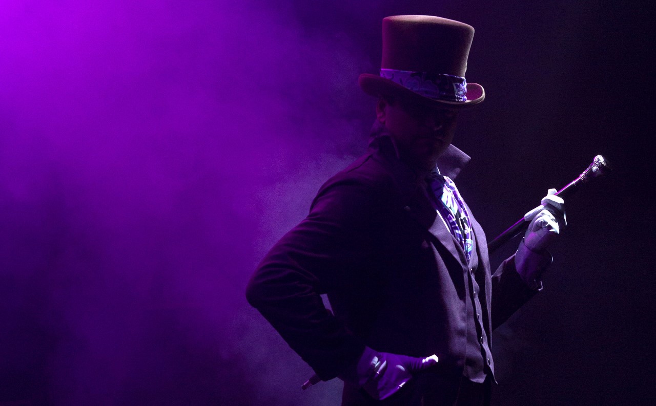Photo: Willy Wonka standing in the spotlight of the stage. Photo courtesy of Alex Malone.