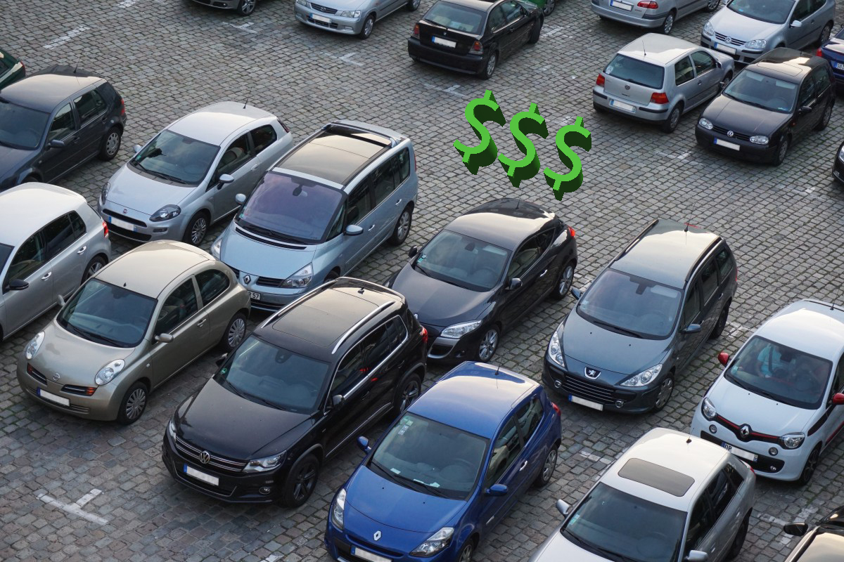 GRAPHIC: Above view angle of cars on a cobblestone parking lot with a 3D graphic of dollar signs between the cars. Graphic by The Signal reporter, Mark Brady.