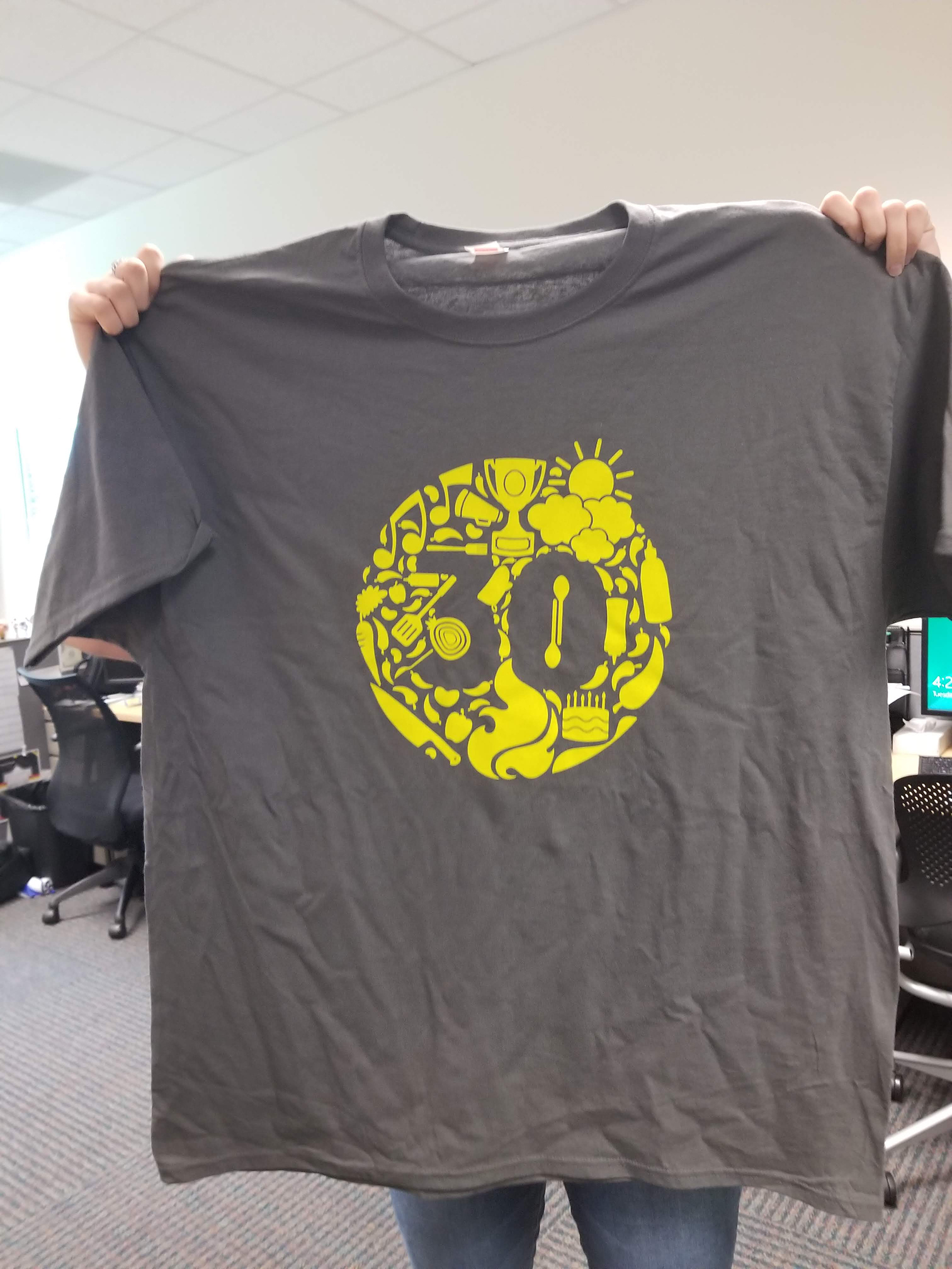 PHOTO: gray t-shirt featuring the number 30 in a yellow circle featuring various cook-off themed symbols. Photo by The Signal reporter Emily Wilkinson.