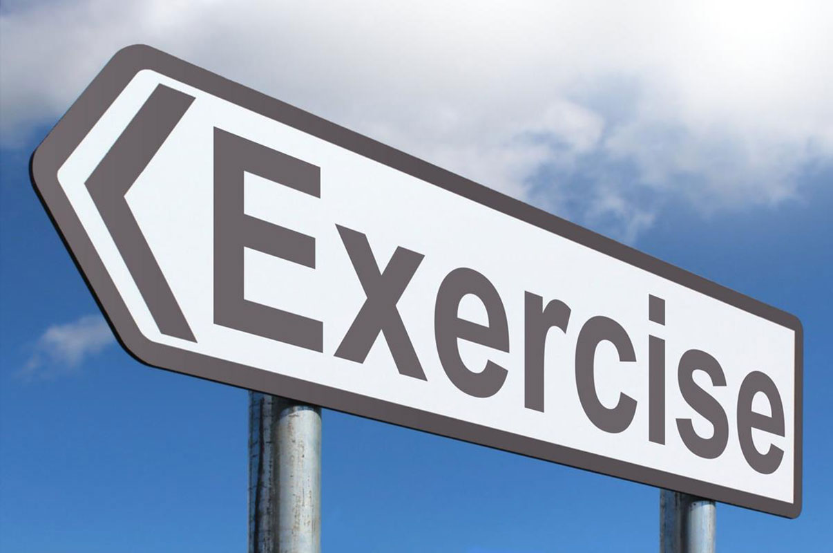 PHOTO: A sign reading "exercise" pointing left in front of the sky. Photo courtesy of Creative Commons.