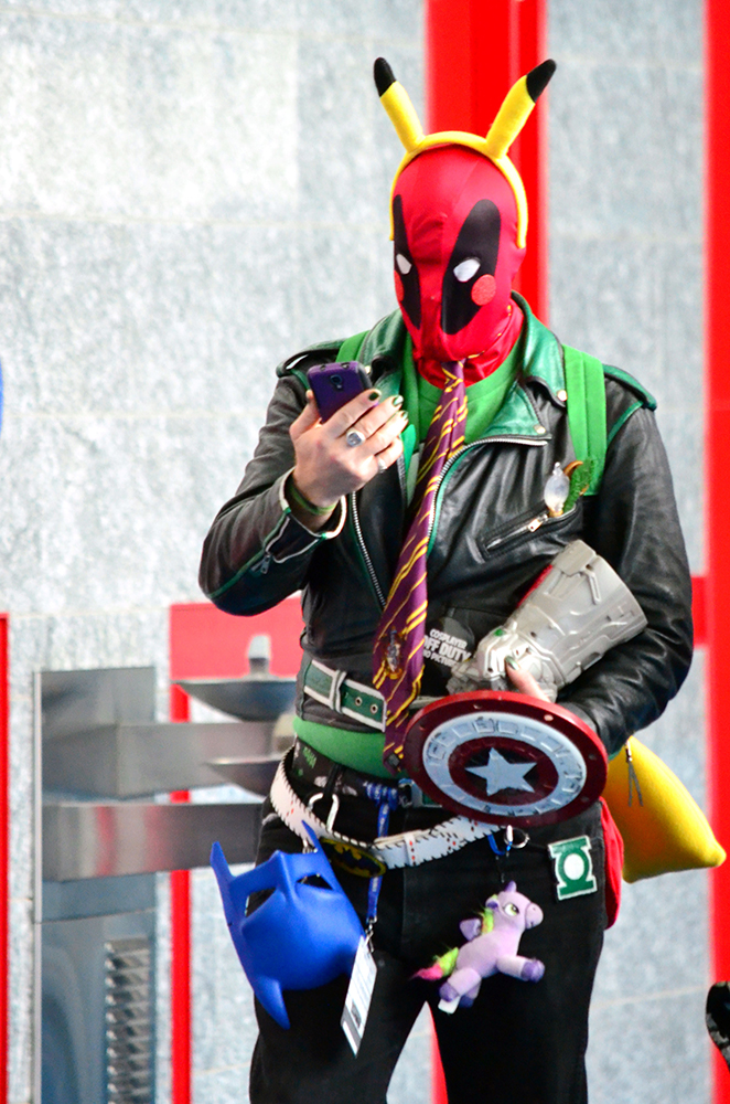 PHOTO: A cosplayers wears various elements from many different characters, to include: a Pikachu ear headband, a Deadpool mask, a Gryffindor tie, a Slytherin jacket, an infinity gauntlet, a mini-Captain America shield, a Green Lantern keychain and a Batman mask. Photo by The Signal reporter Jennifer Martinez.