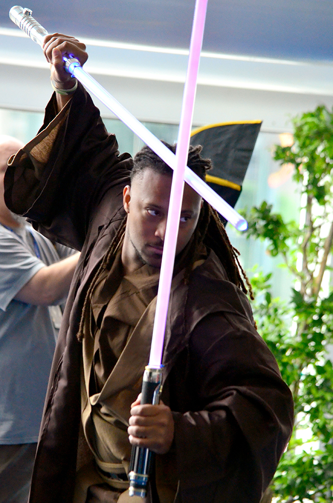 PHOTO: A man dressed as a Jedi from Star Wars pauses in a battle pose with a purple and blue lightsaber. Photo by The Signal reporter Jennifer Martinez.