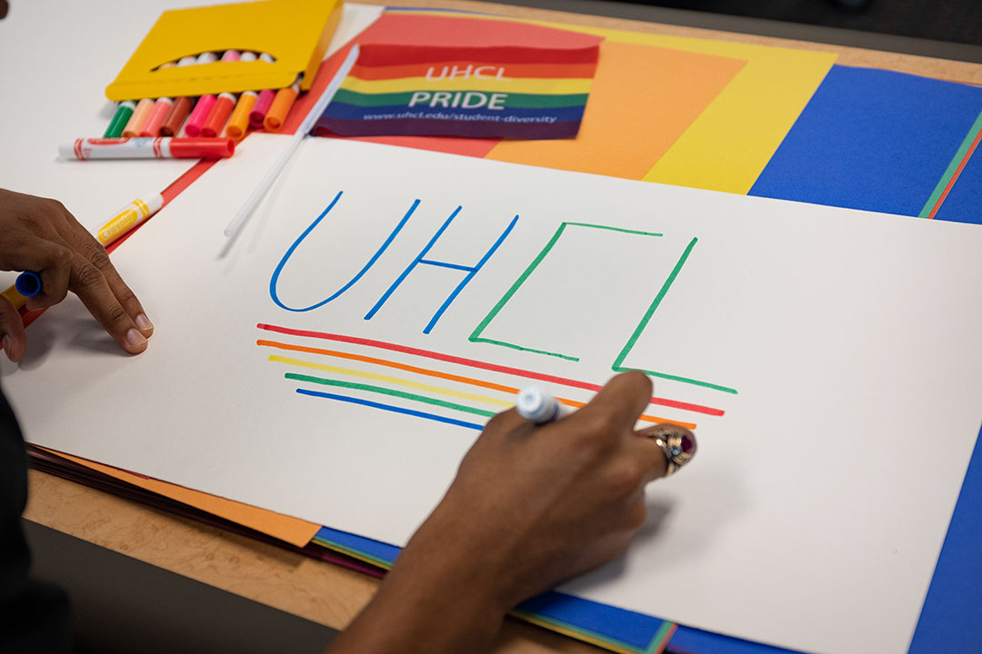PHOTO: White sign with "UHCL" written on it and rainbow colored lines underlining the letters. Photo by The Signal reporter Kirk McDaniel.