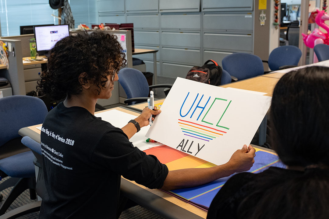 PHOTO: Student Arturo Guerra holds up finished sign reading "UHCL Ally." Photo by The Signal Kirk McDaniel.
