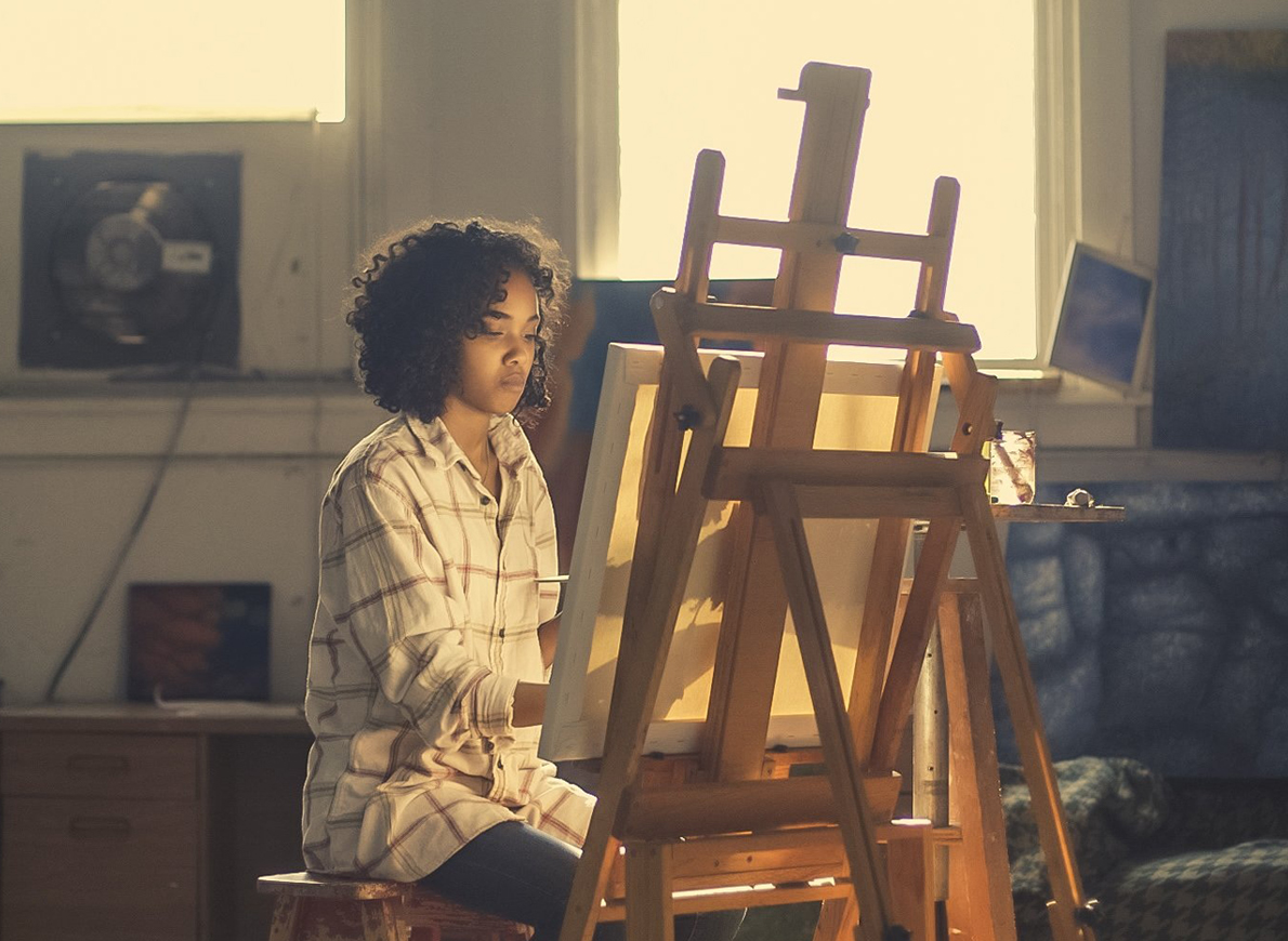 PHOTO: Young black women paints on canvas. Photo by bridgesward from Pixabay. SOURCE: https://pixabay.com/photos/artist-painter-easel-canvas-2578454/