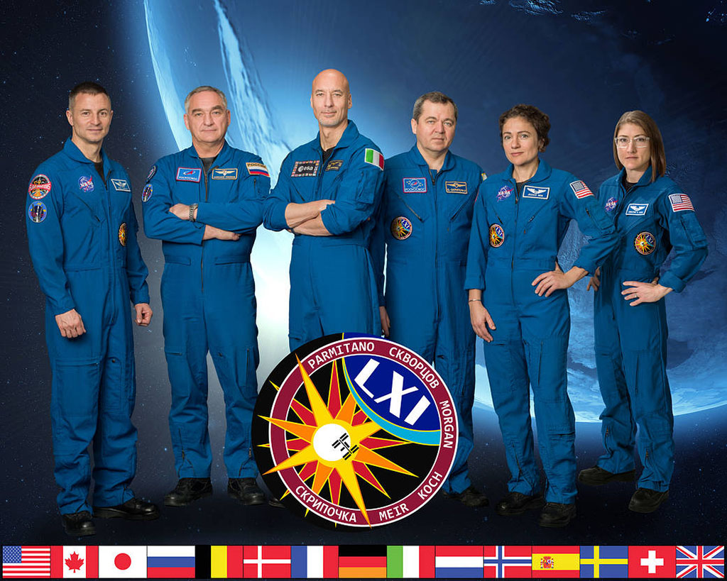PHOTO: Flight crew of Expedition 61 with a graphic of their mission patch. Photo by Robert Markowitz courtesy of NASA.