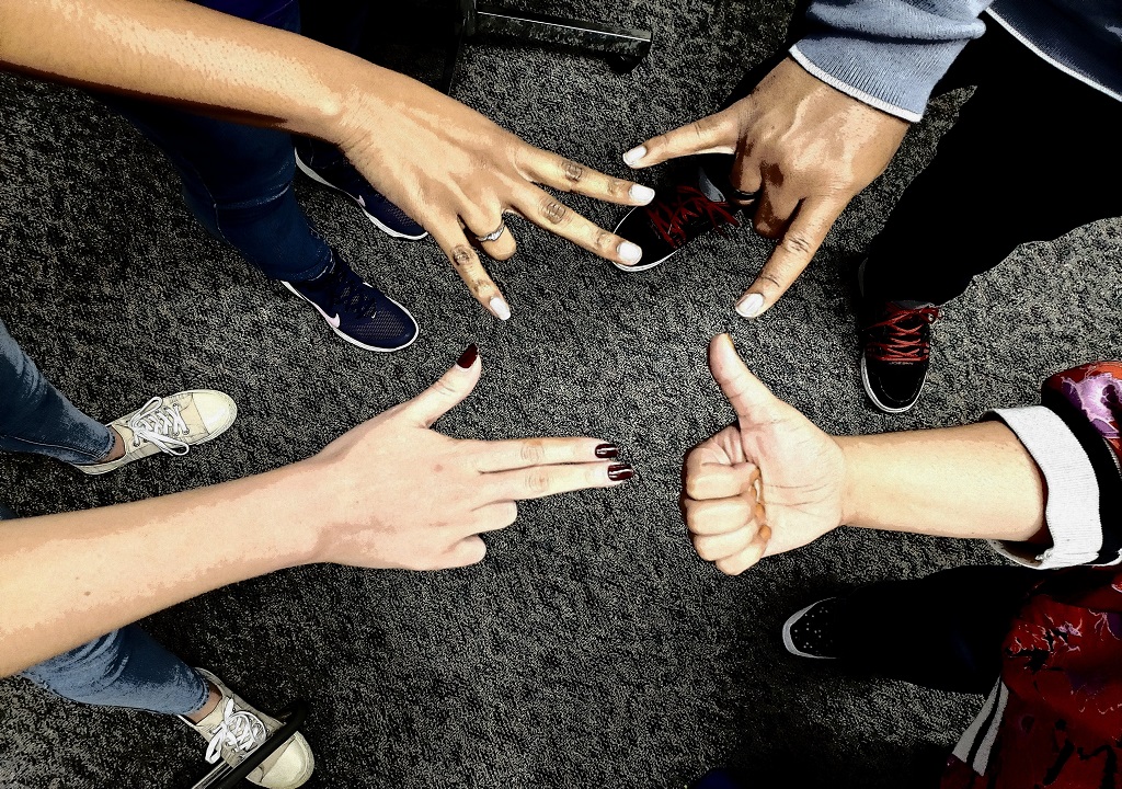 PHOTO: Photo of students making university hand signs while in a circle.