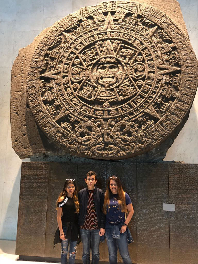 PHOTO: Ximena Flandes (left) and her family visiting the Aztec sun stone. Photo courtesy of Ximena Flandes.