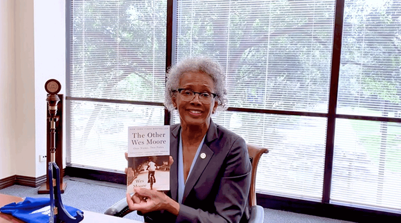 Photo: President Blake sitting in her office holding a copy of "The Other Wes Moore: One Name, Two Fates," the 2020-2021 book selection for the Common Reader Program.