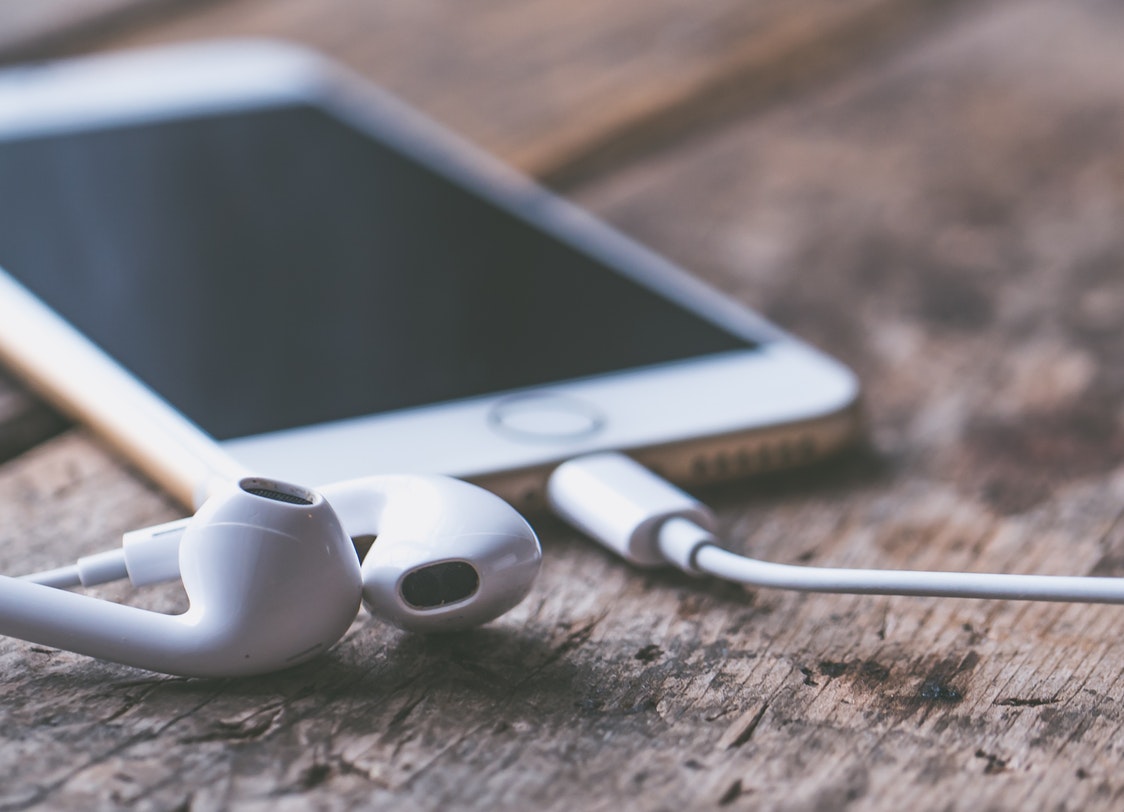 PHOTO: An iPhone in the background with headphones connected. Photo courtesy of Jessica Lewis via Pexels.com. SOURCE: https://www.pexels.com/photo/background-blur-business-close-up-583843/.