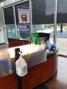 PHOTO: Dean of Students front desk in SSCB with hand sanitizer and plexiglass shield. Students can obtain single-use masks and hand sanitizing spray here if they forget it. Photo by Lindsay Humphrey.