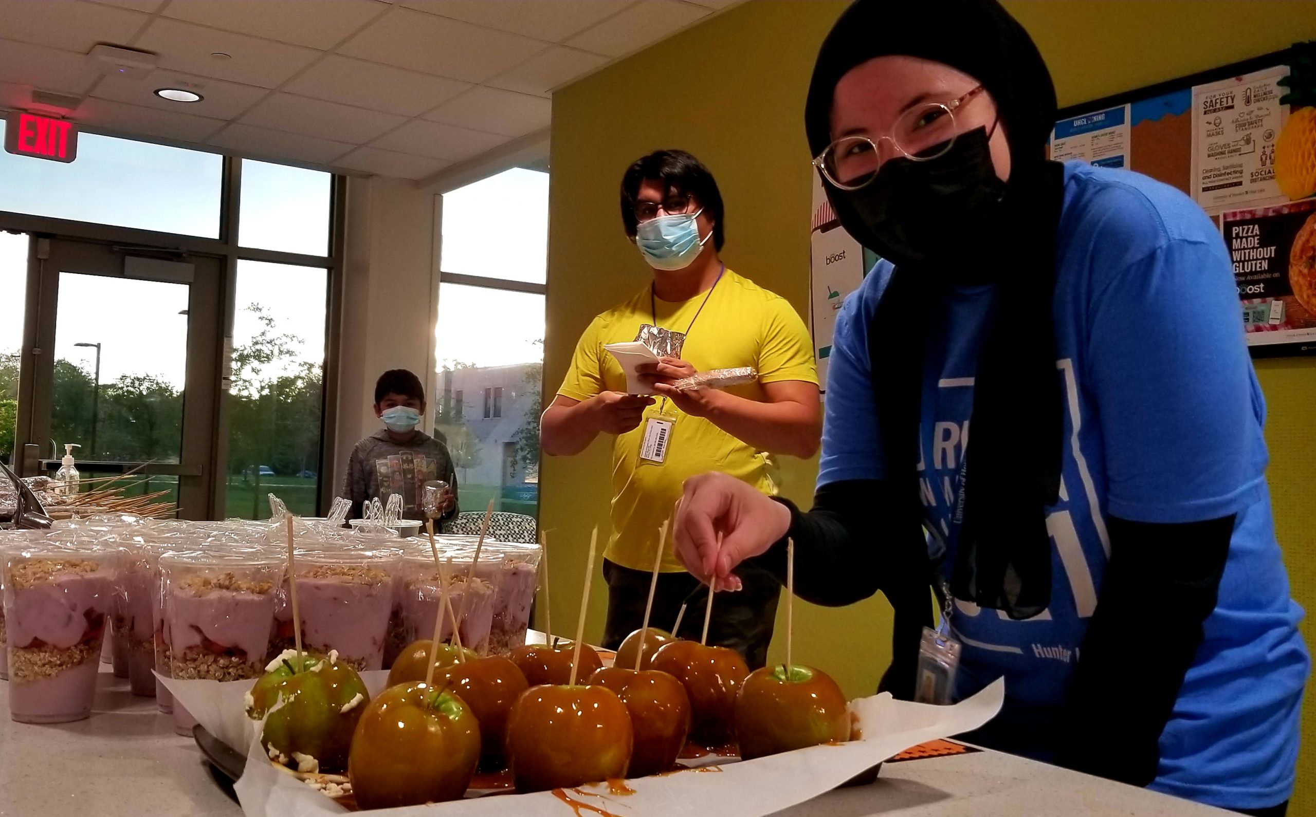 PHOTO: Hunter Hall residents Dylan Bucio (left) and Biancarosa Vargas (right) served caramel apples and parfaits, among other foods for the carnival event held to celebrate residents’ return to the hall. Photo courtesy of UHCL Student Housing and Residence Life.