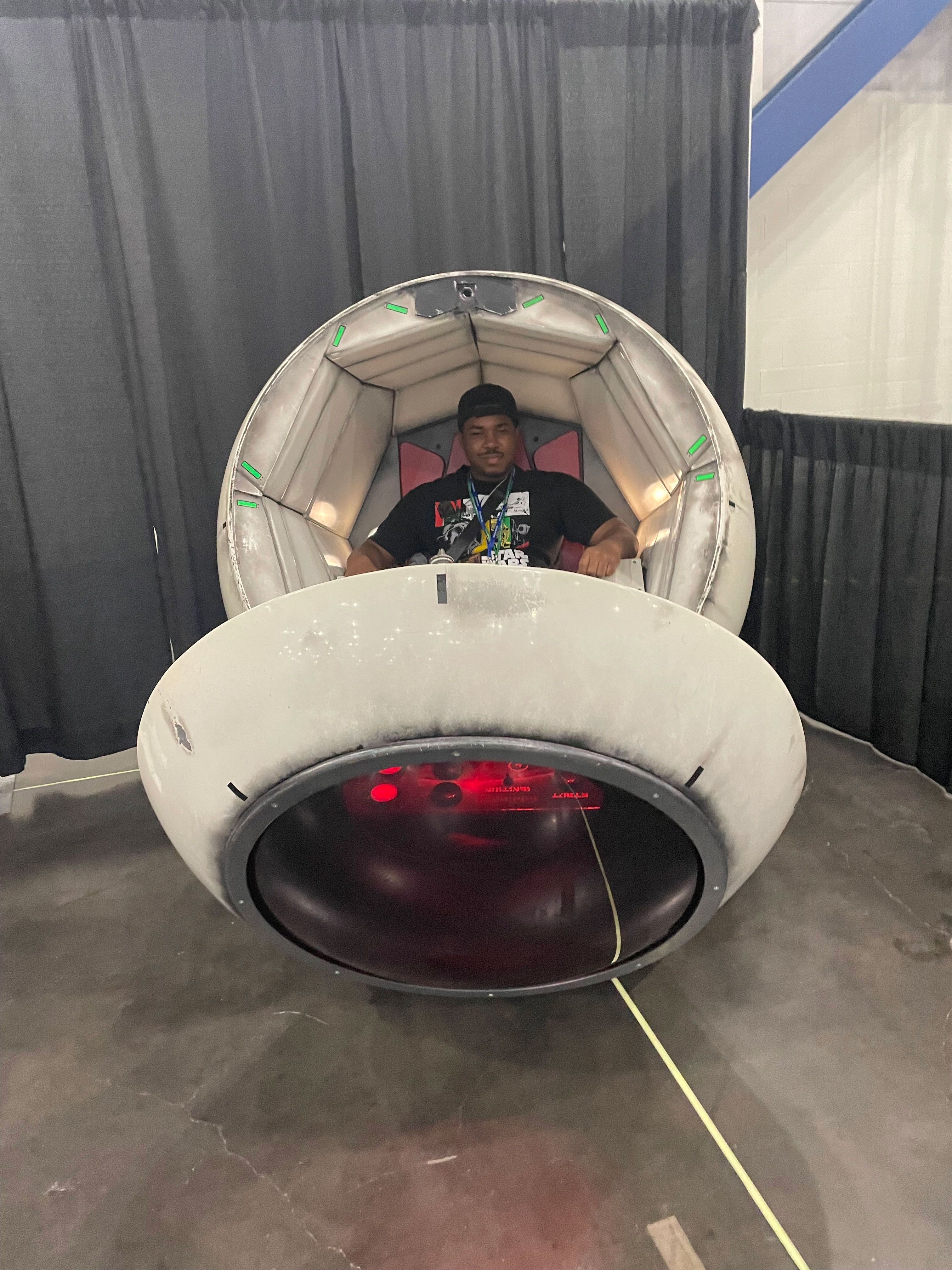PHOTO: Image depicts boy in Star Wars shirt with hat sitting inside a space pod modeled after pod from Dragon Ball Z. Photo by The Signal Managing Editor of Content and Operations Troylon Griffin II.
