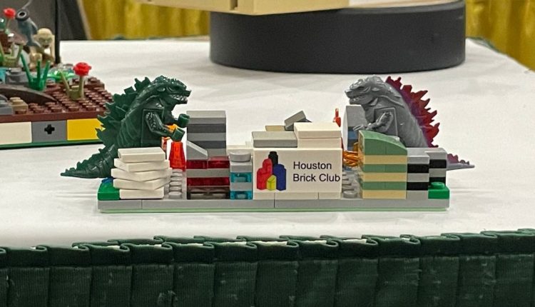PHOTO: Miniature lego blocks stacked as barriers between one green lego dinosaur and one gray lego dinosaur looking at each other. Photo by Audience Engagement Editor Stephanie Perez.