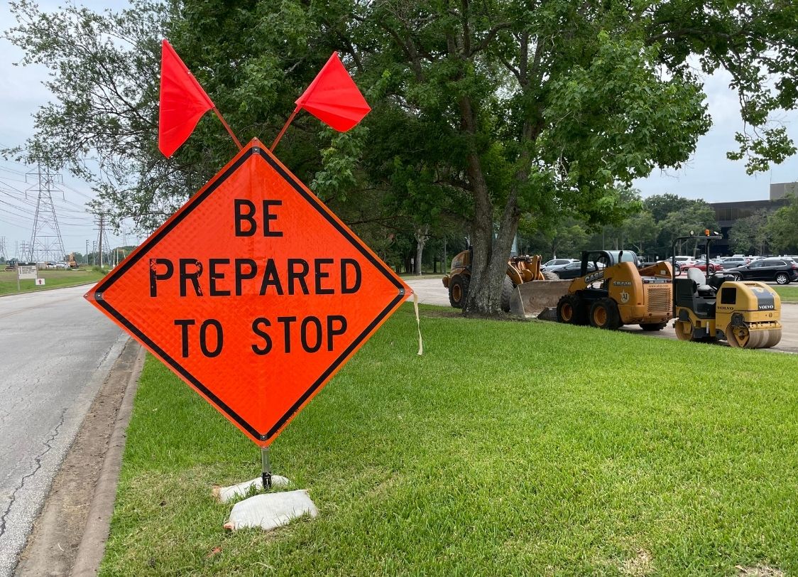PHOTO: Orange construction sign on the grass with construction vehicles on the right. Photo by Audience Engagement Editor Stephanie Perez.