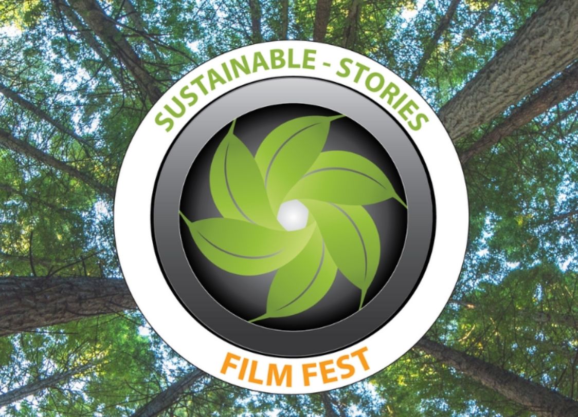 GRAPHIC: Background with a view of the trees. In the middle there is a graphic of a camera lens with leaves that create a camera shutter in the middle. Courtesy of the Sustainable Stories Film Fest.