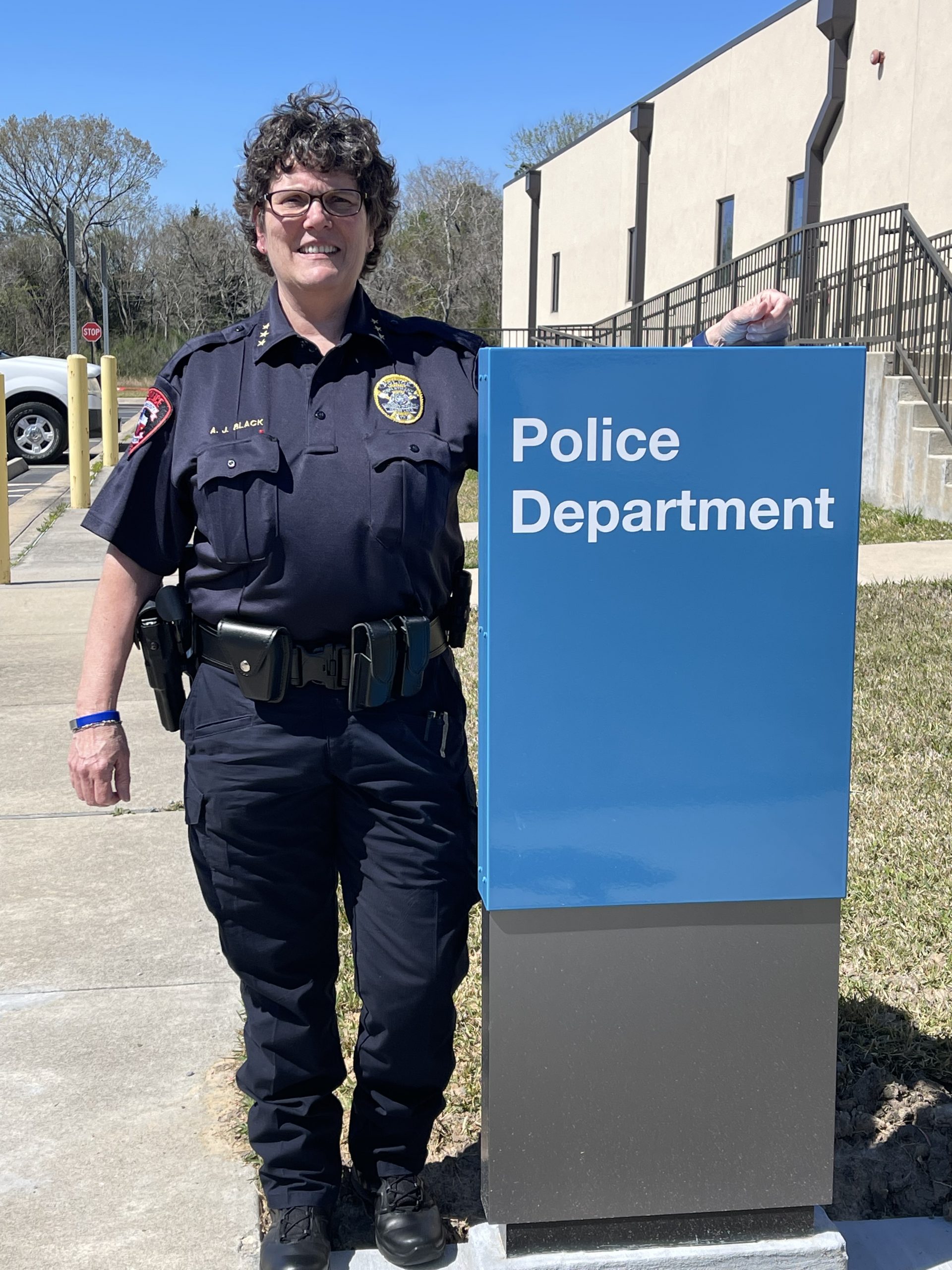 IMAGE: UHCL Assistant Chief of Police Andrea Black stands next to UHCL campus police department sign in uniform.