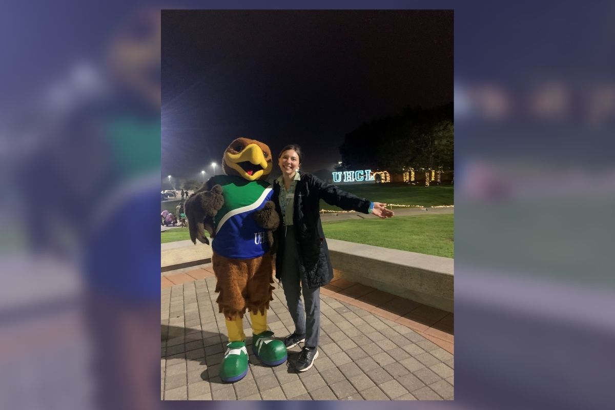 GRAPHIC: Shelby Kuepker pictured next to Hunter the Hawk in front of the UHCL letters in Alumni Plaza. In the background, the image is blurred with a blue overlay. Photo Courtesy of Shelby Kuepker.