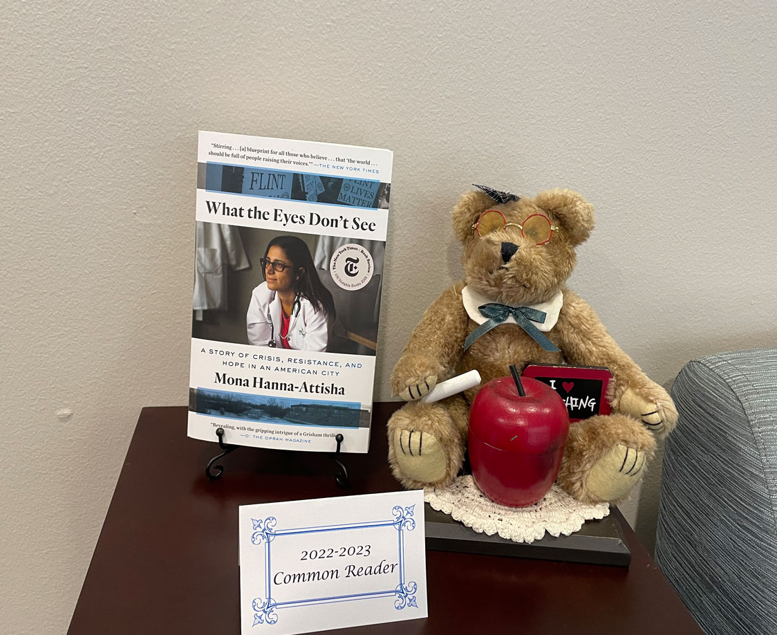 PHOTO: Image shows book "What the Eyes Don't See" by Mona Hanna-Attisha. The book is next to a teddy bear with an apple and a card that says "2022-2023 Common Reader." Photo by The Signal Managing Editor Troylon Griffin II.