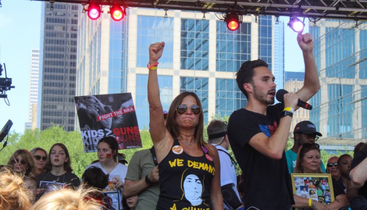 PHOTO: David Hogg speaks alongside a fellow gun control activist with their fist raised. A group of children and protest organizers stand behind them. Photograph by The Signal Managing Editor Cesar Cardenas.