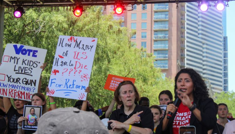 PHOTO: Linda Hidalgo speaks on stage along side a sign language interpreter and two signs held behind her. Photograph by The Signal Managing Editor Cesar Cardenas.