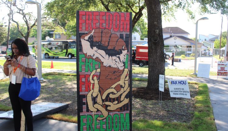 This sign features the word freedom six times descending down the sign. The colors rotate from red to black to green. The middle of the sign is a balled fist breaking out from chains. Photograph by The Signal reporter Jared Cadore.