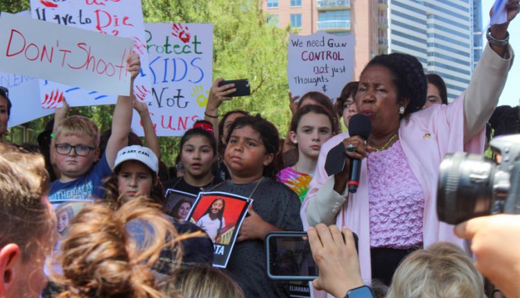PHOTO: Sheila Jackson Lee hold a group of paper in her hand raised in the air .Along side her are various children holding signs calling for gun control. Photograph by The Signal Managing Editor Cesar Cardenas.