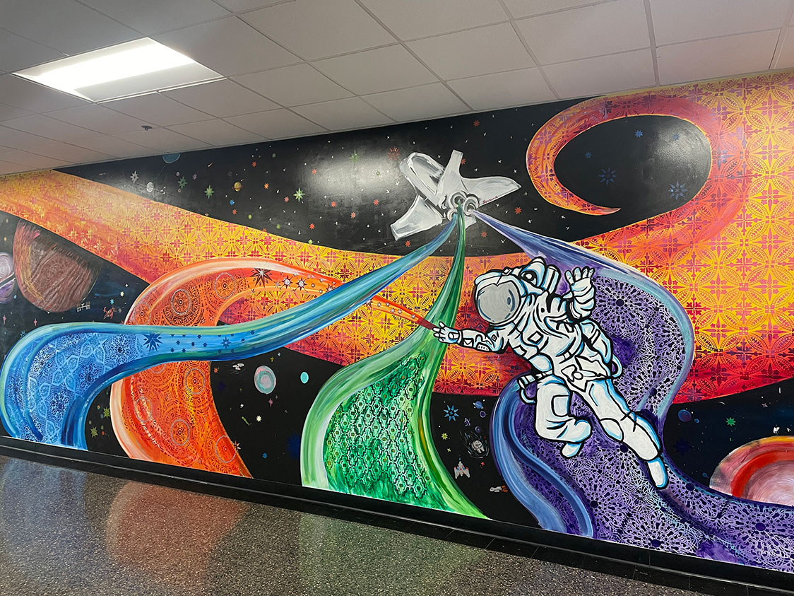 PHOTO: Image depicts mural painted on wall. The mural shows two astronauts with paint brushes. Bright colors flow out the paint brush throughout space. Photo by The Signal Executive Editor Troylon Griffin II.