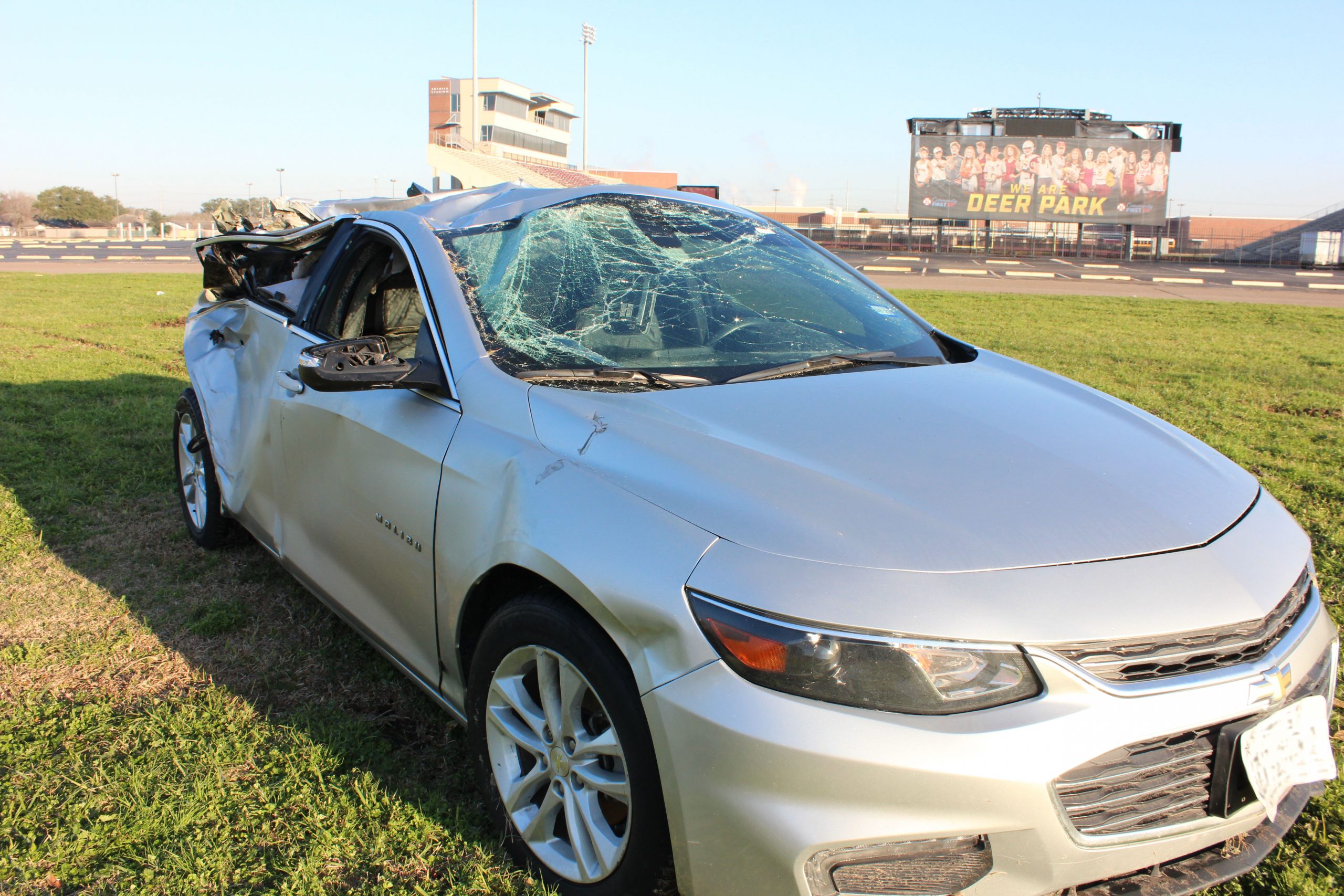 A car that was picked up by a tornado and dropped in a field near Deer Park high school's football stadium. A big sign with the football team on it in the back that says "We are Deer Park"