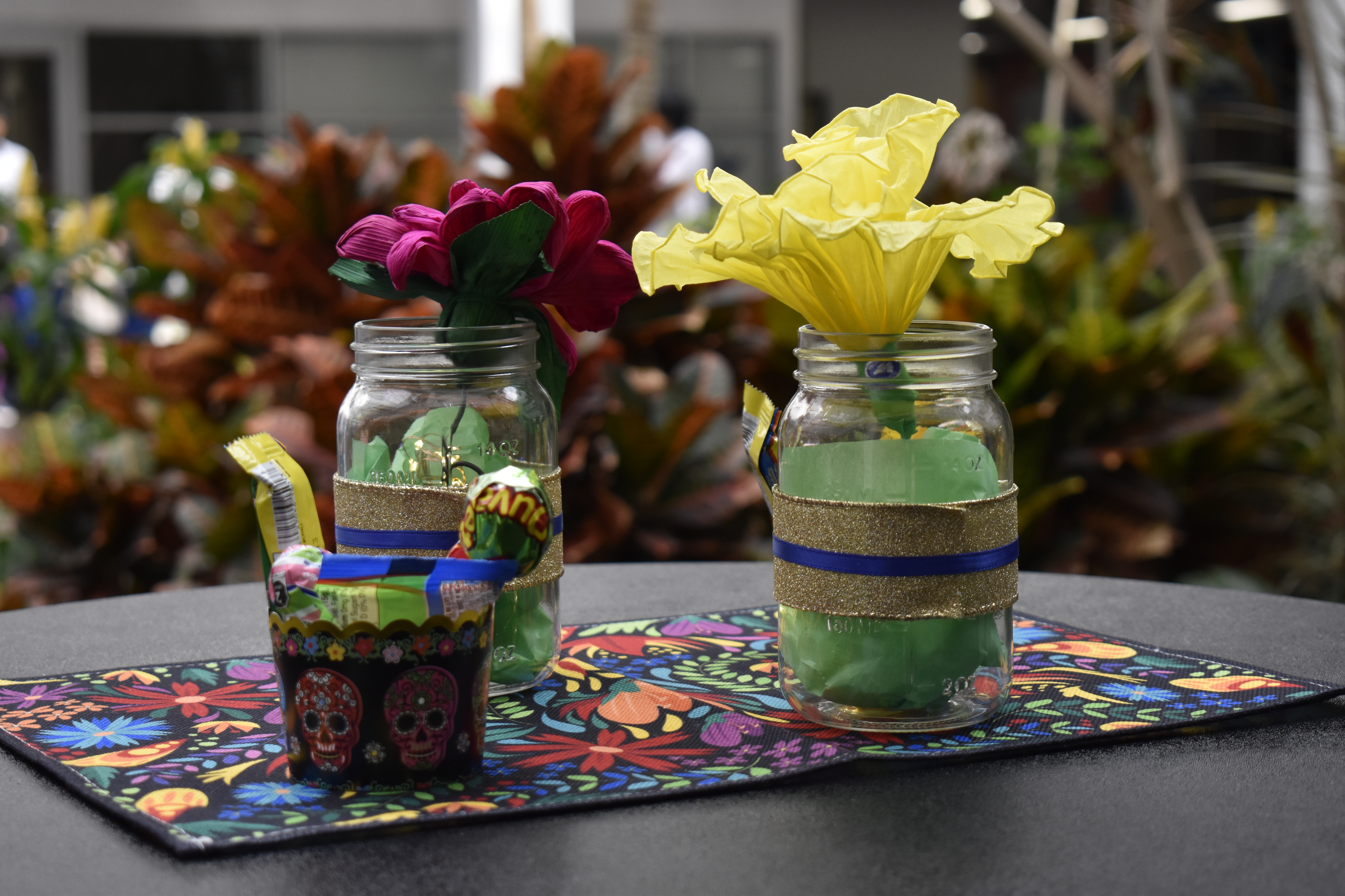 A festive table display of bright colors such as flowers and sugar skulls.