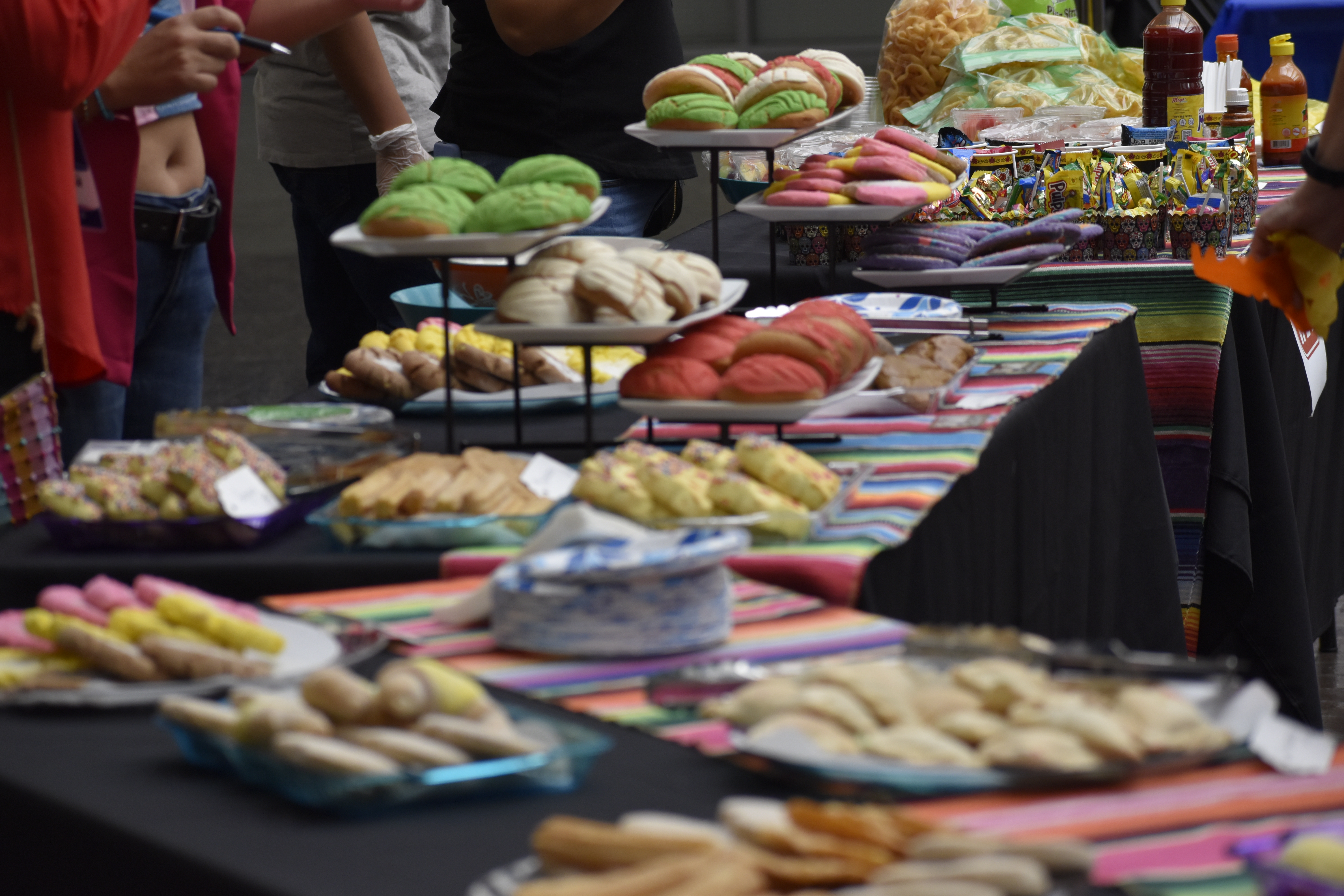 Many tables filled to the brim with many Hispanic desserts and treats.
