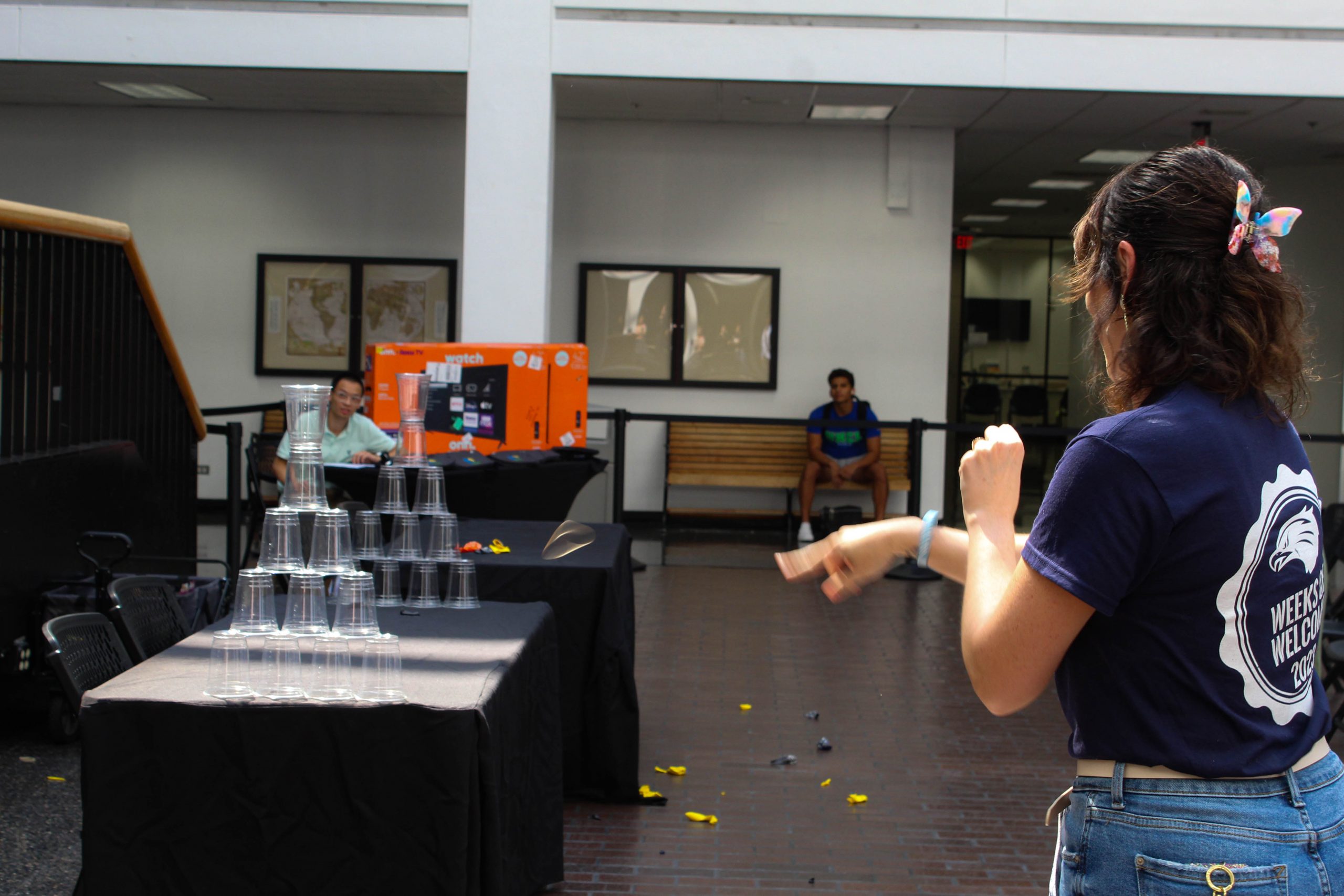 A student shooting rubber bands at a stack of cups.